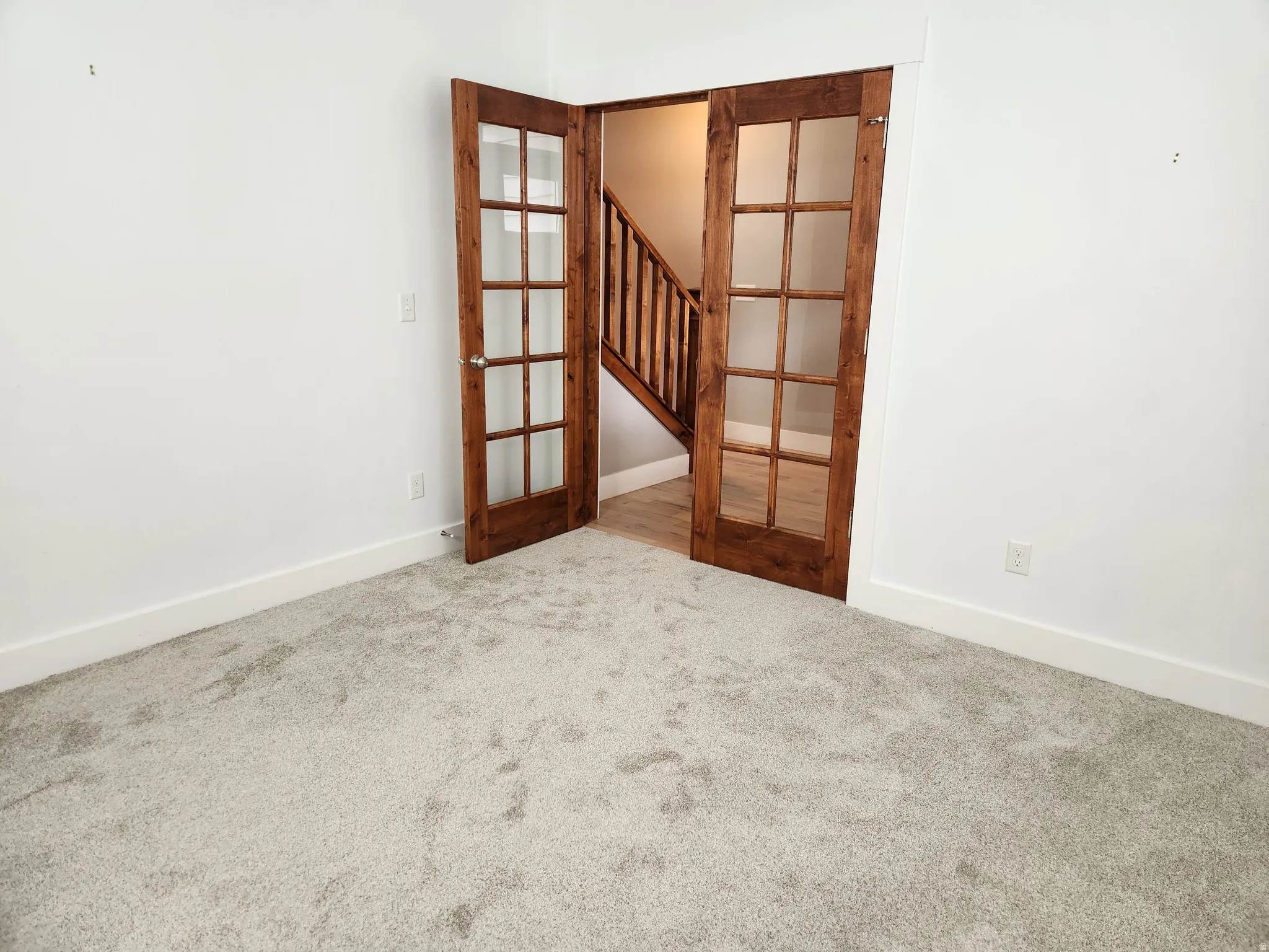 Room featuring light-toned carpeting and white walls with baseboards
