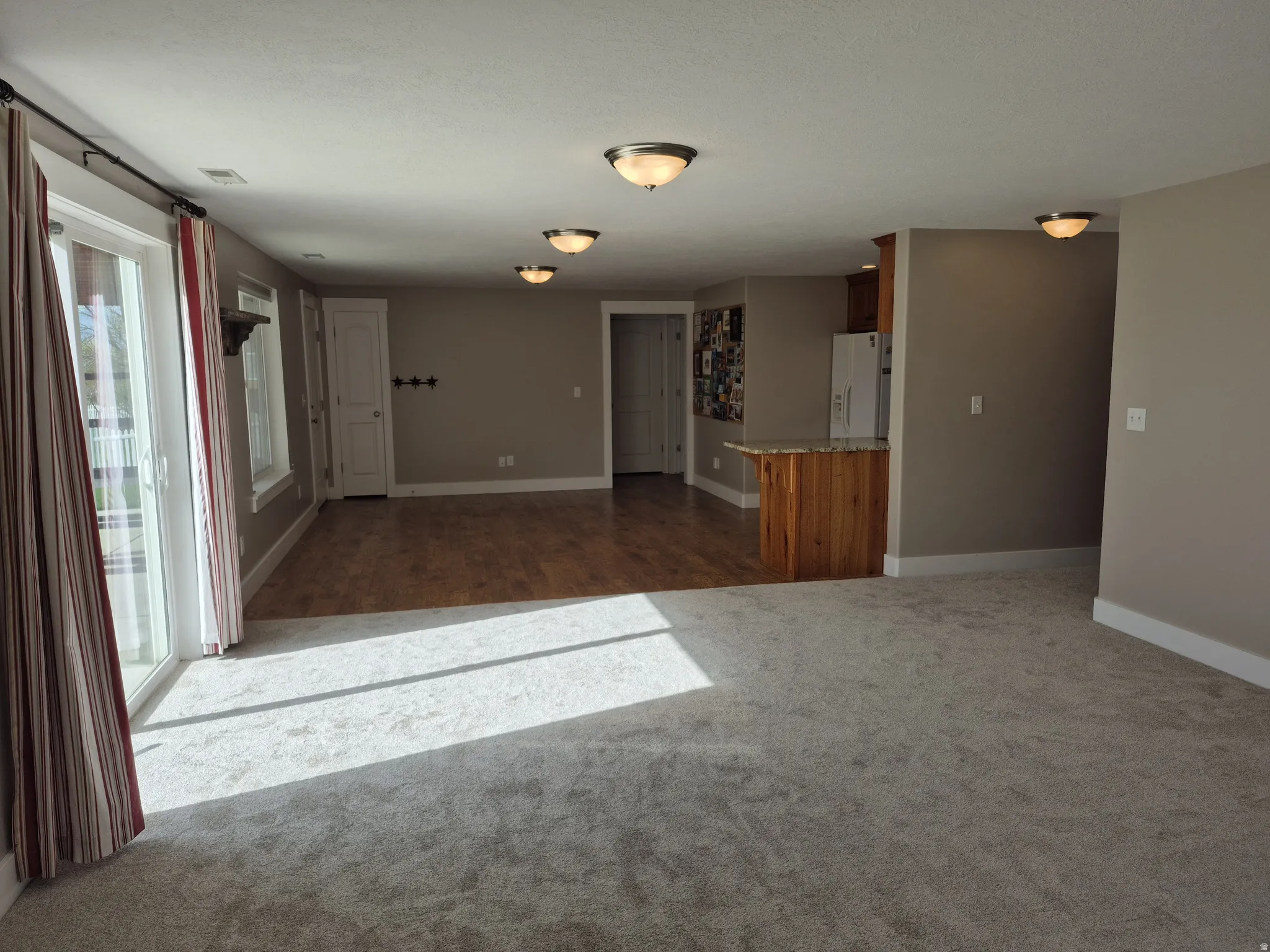Spacious interior featuring a combination of light-toned carpeting and wood-finish flooring in kitchen/dining area