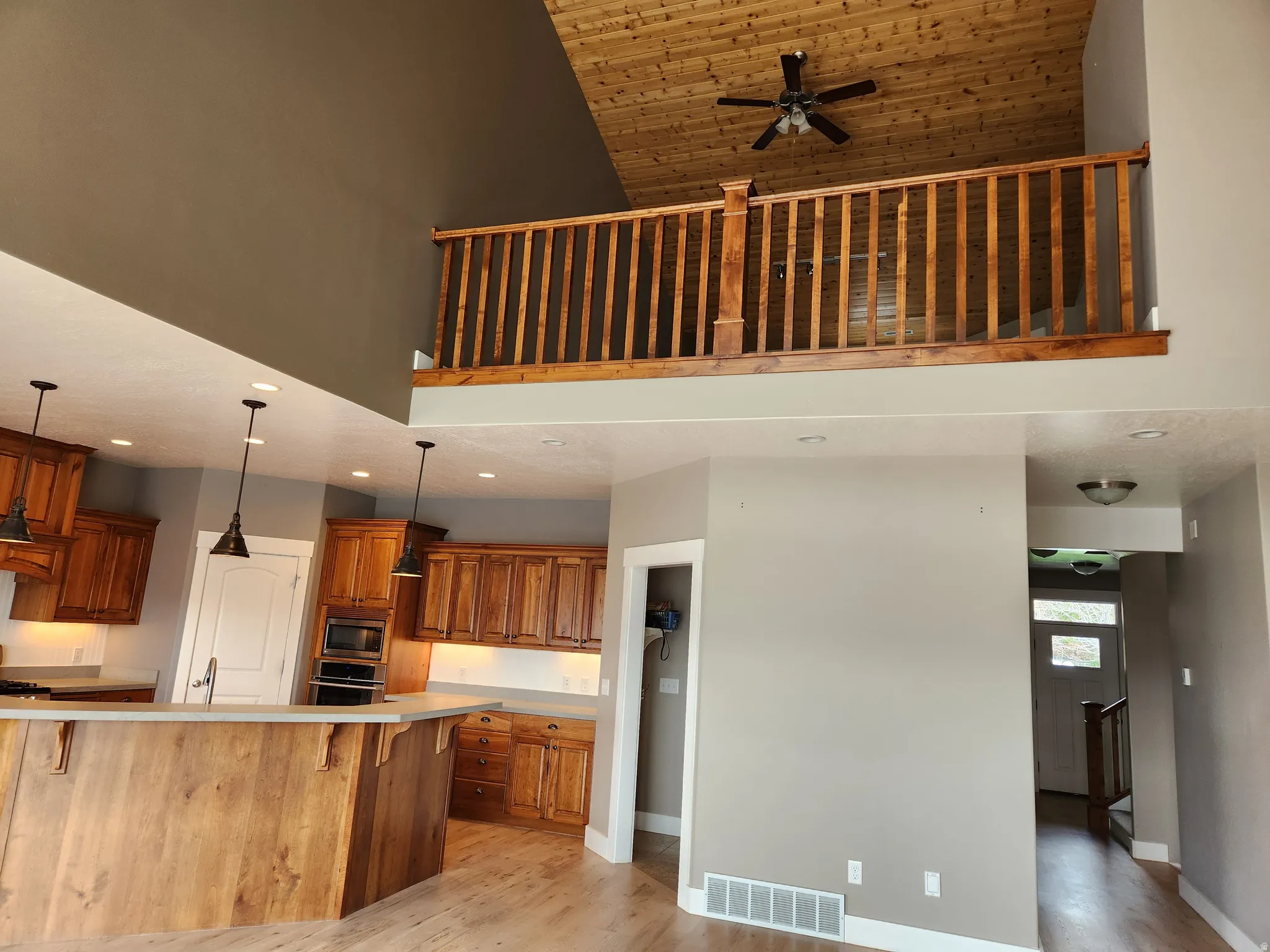 Open concept living space featuring a wood-finish ceiling, a ceiling fan, and an upper-level wood railing