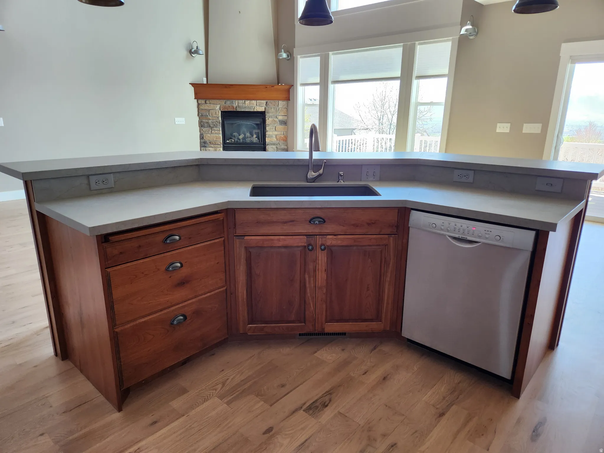 Kitchen island with a light-toned quartz countertop, integrated sink, and wood cabinetry