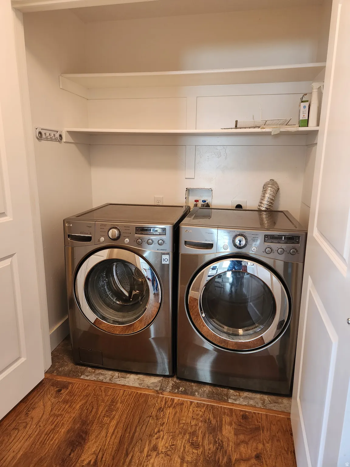 Dedicated second laundry closet in the basement featuring a built-in shelf system, wood-finish flooring, and white bifold doors. Additional laundry on the main floor.