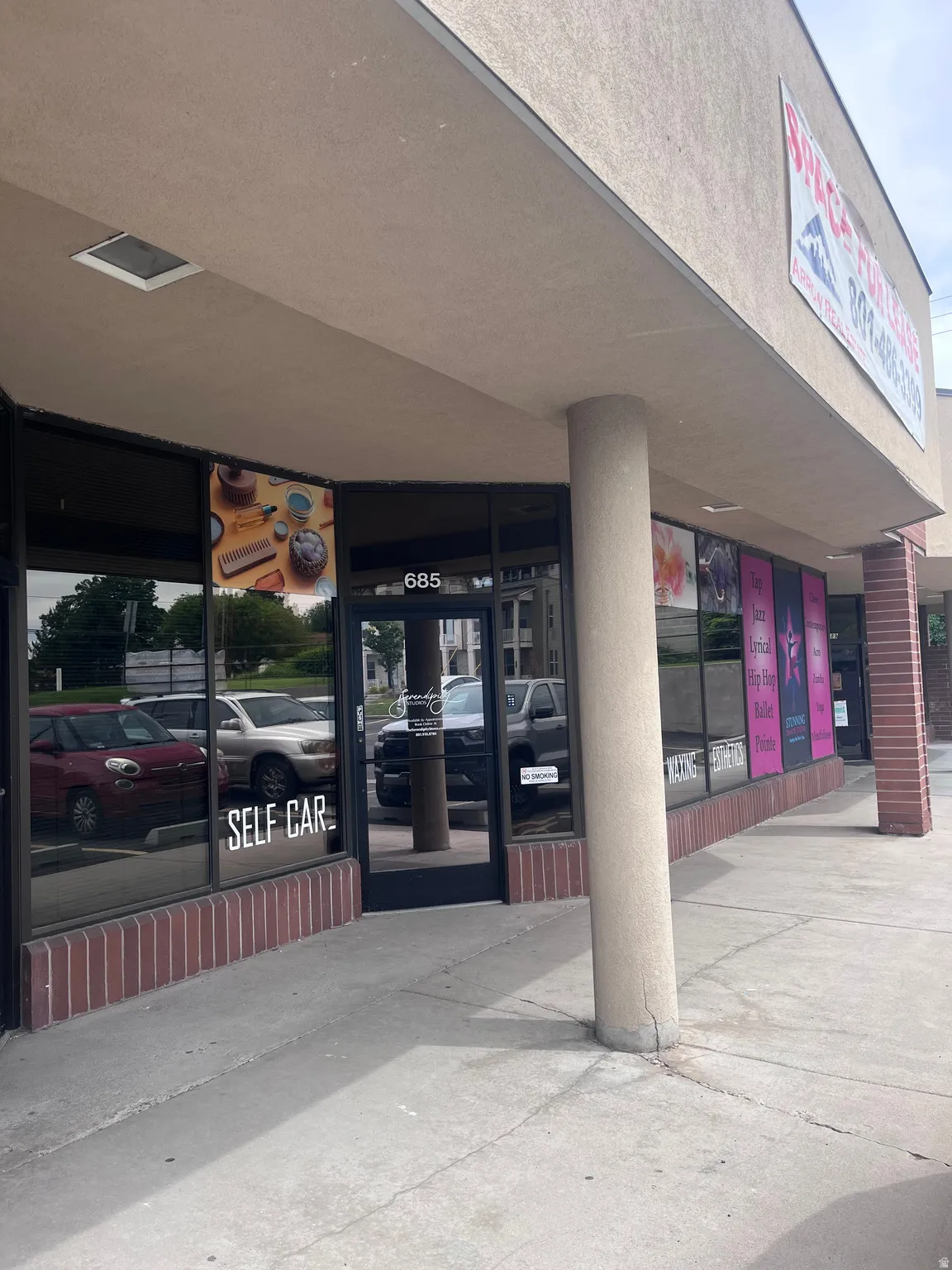 Commercial storefront featuring expansive display windows, a recessed entrance, and a number 685 address marker