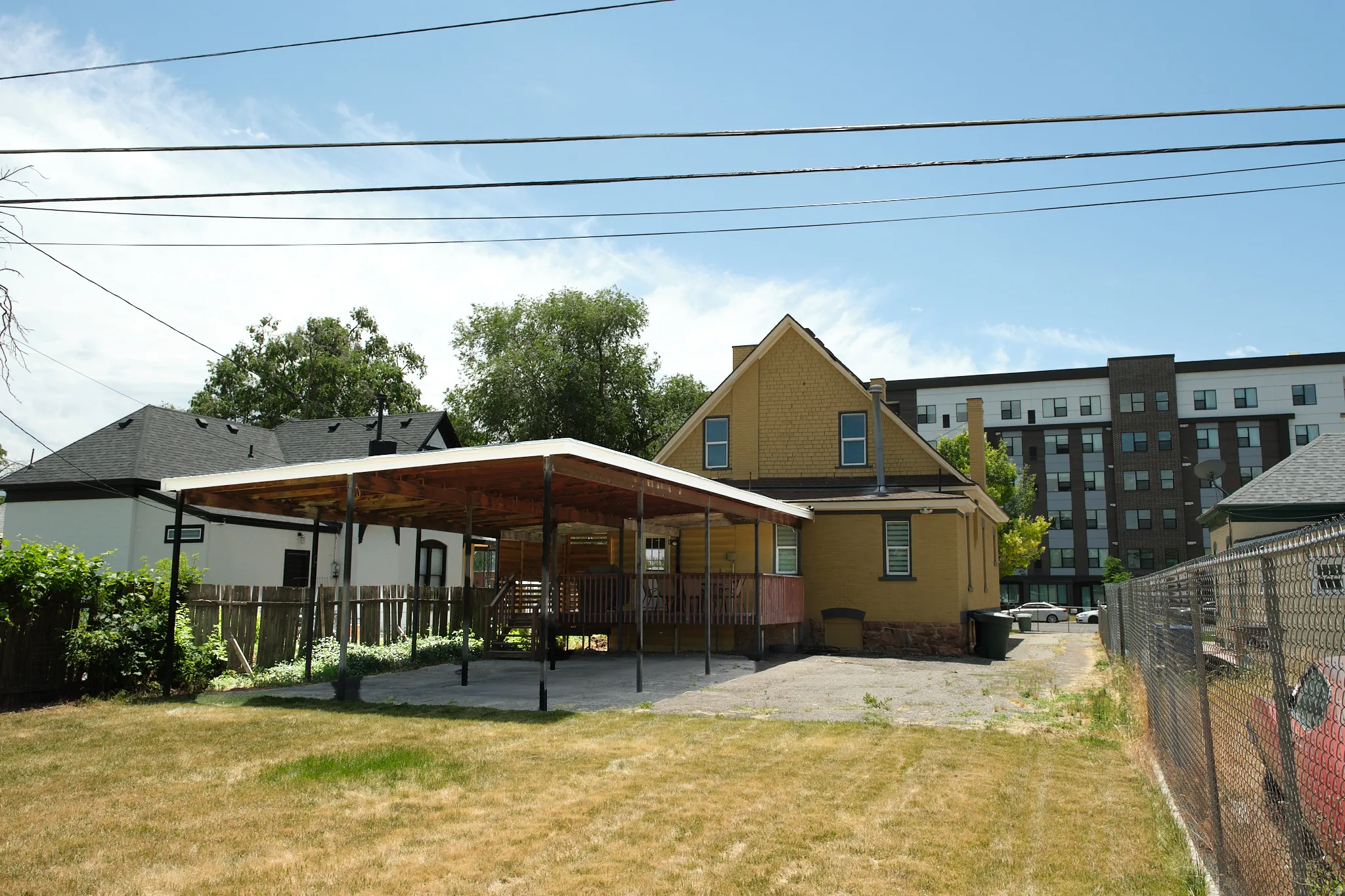Rear exterior with yellow siding and a covered patio area. Covered parking for three vehicles.