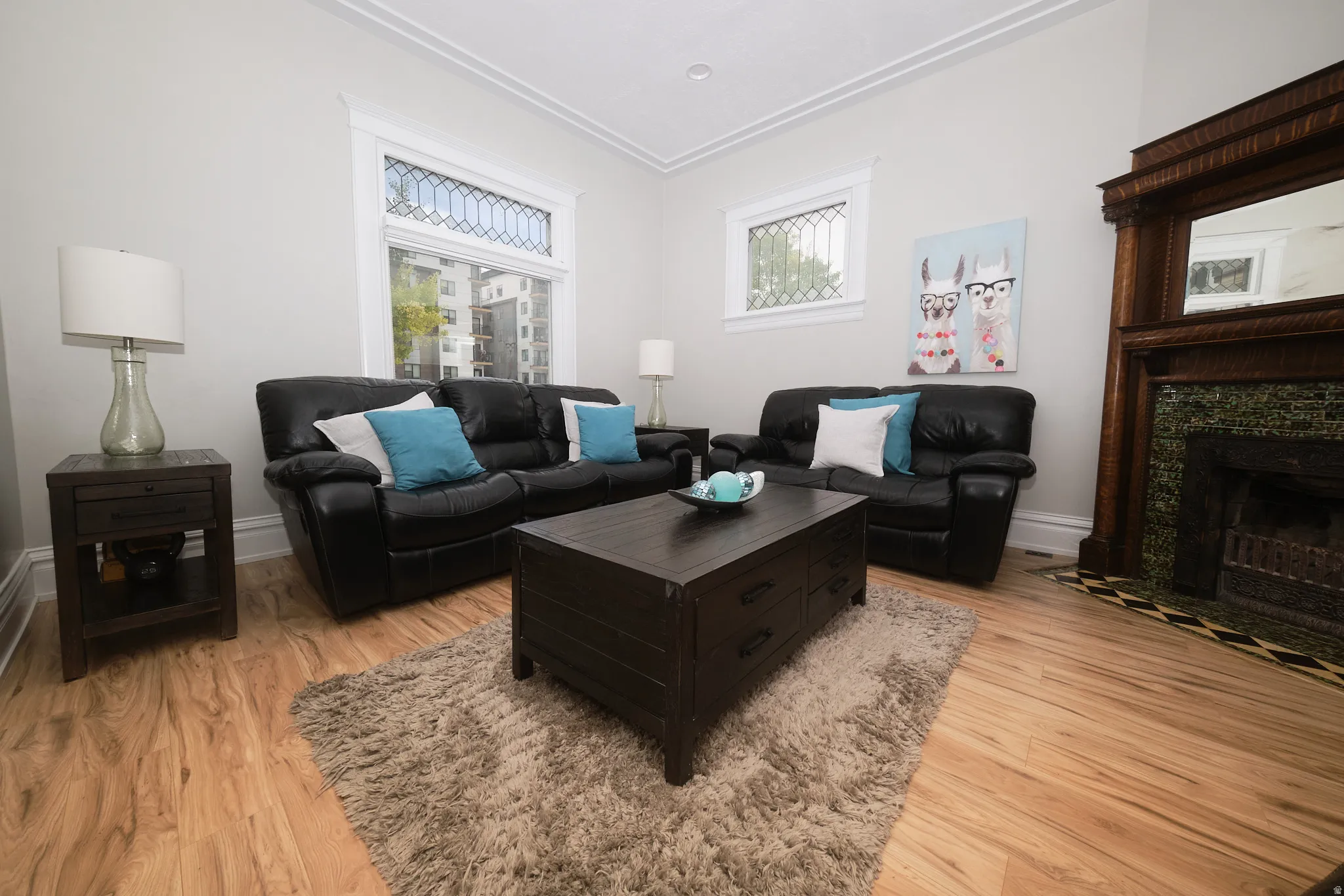 Living area featuring wood-finish flooring, beautiful fireplace,  white crown molding, and windows with decorative grilles