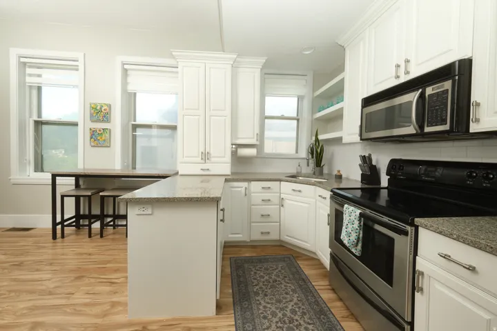 Contemporary kitchen with white cabinetry, stainless steel appliances, and light-toned wood-finish flooring