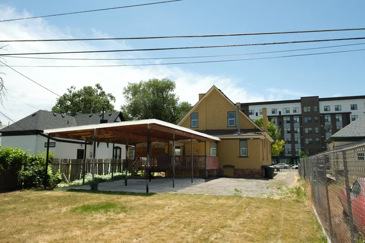 Rear exterior with yellow siding and a covered patio area. Covered parking for three vehicles.