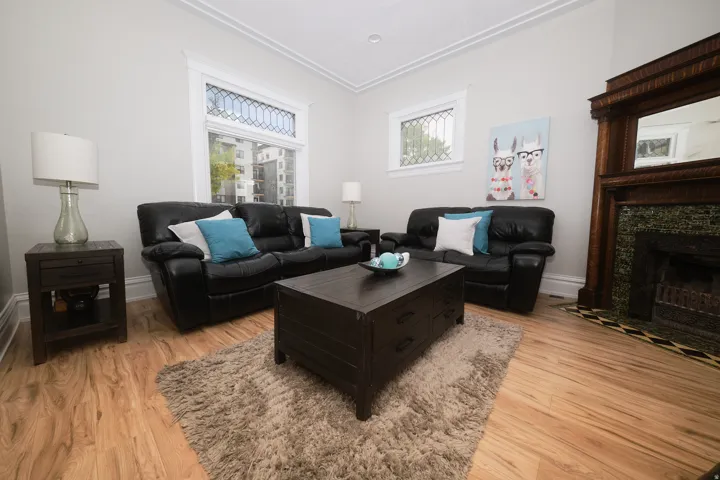 Living area featuring wood-finish flooring, beautiful fireplace,  white crown molding, and windows with decorative grilles