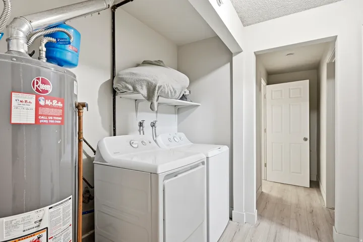 Dedicated laundry area featuring a washer and dryer, an overhead shelf, a water heater, and light wood-finish flooring