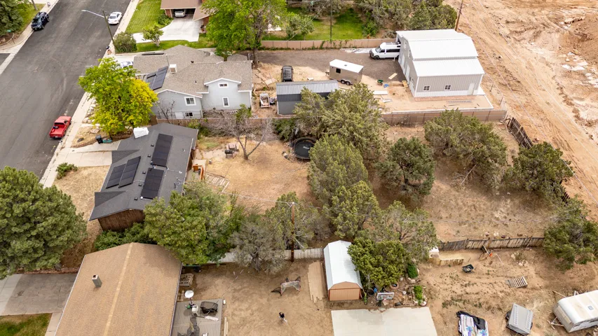 Expansive property featuring a grey two-story residence with solar panels, a detached workshop building, and a large additional structure with a metal roof