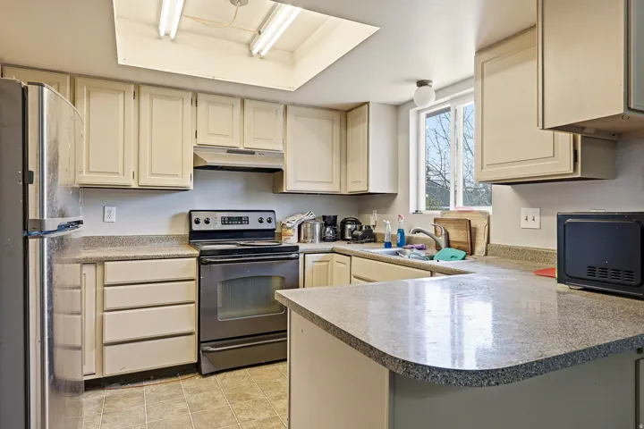 Kitchen featuring light-toned cabinetry, a stainless steel range, and a dual-basin sink under a window
