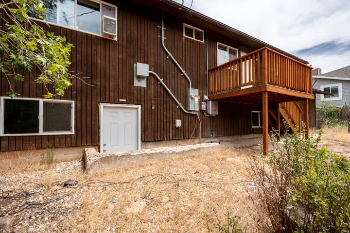 Dark wood-panel siding property featuring a second-story wood deck with railing and stairs