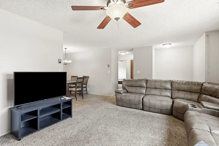 Carpeted living area with a ceiling fan light fixture and recessed lighting