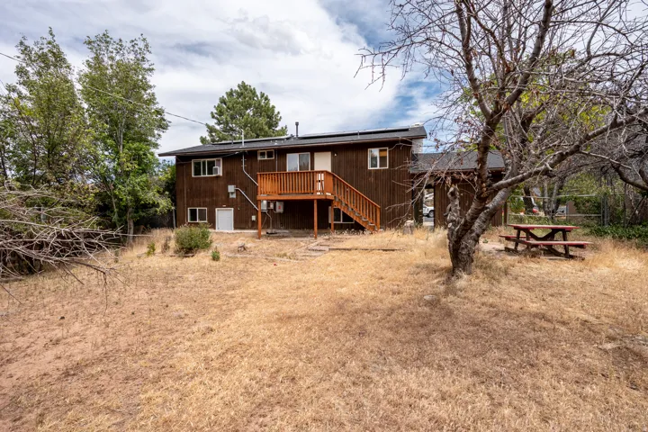 Rear exterior featuring wood siding, a second-story deck with wood railing, an exterior staircase, and an entrance door