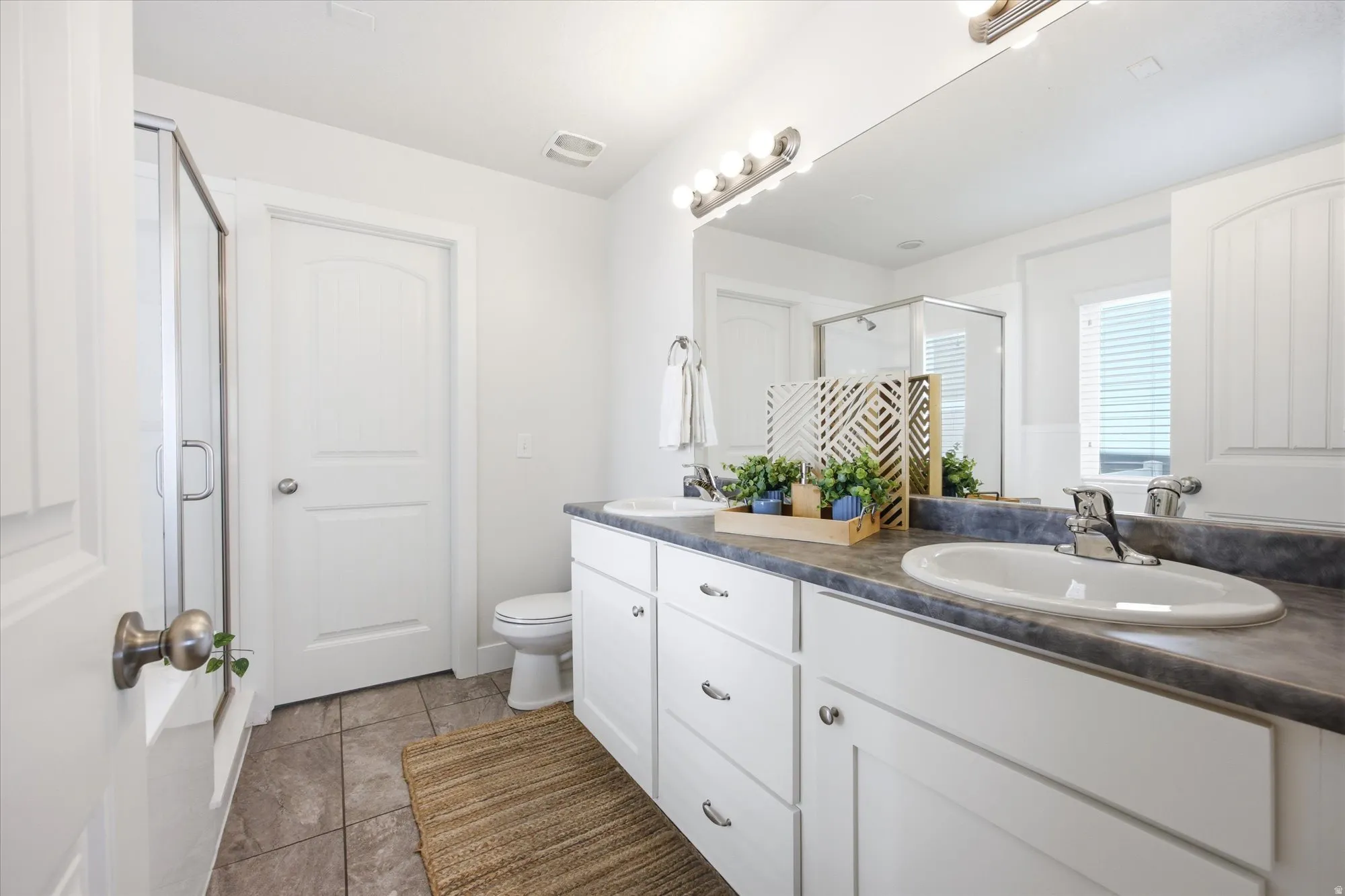 Dual vanity with white cabinetry, a dark countertop, and undermount sinks