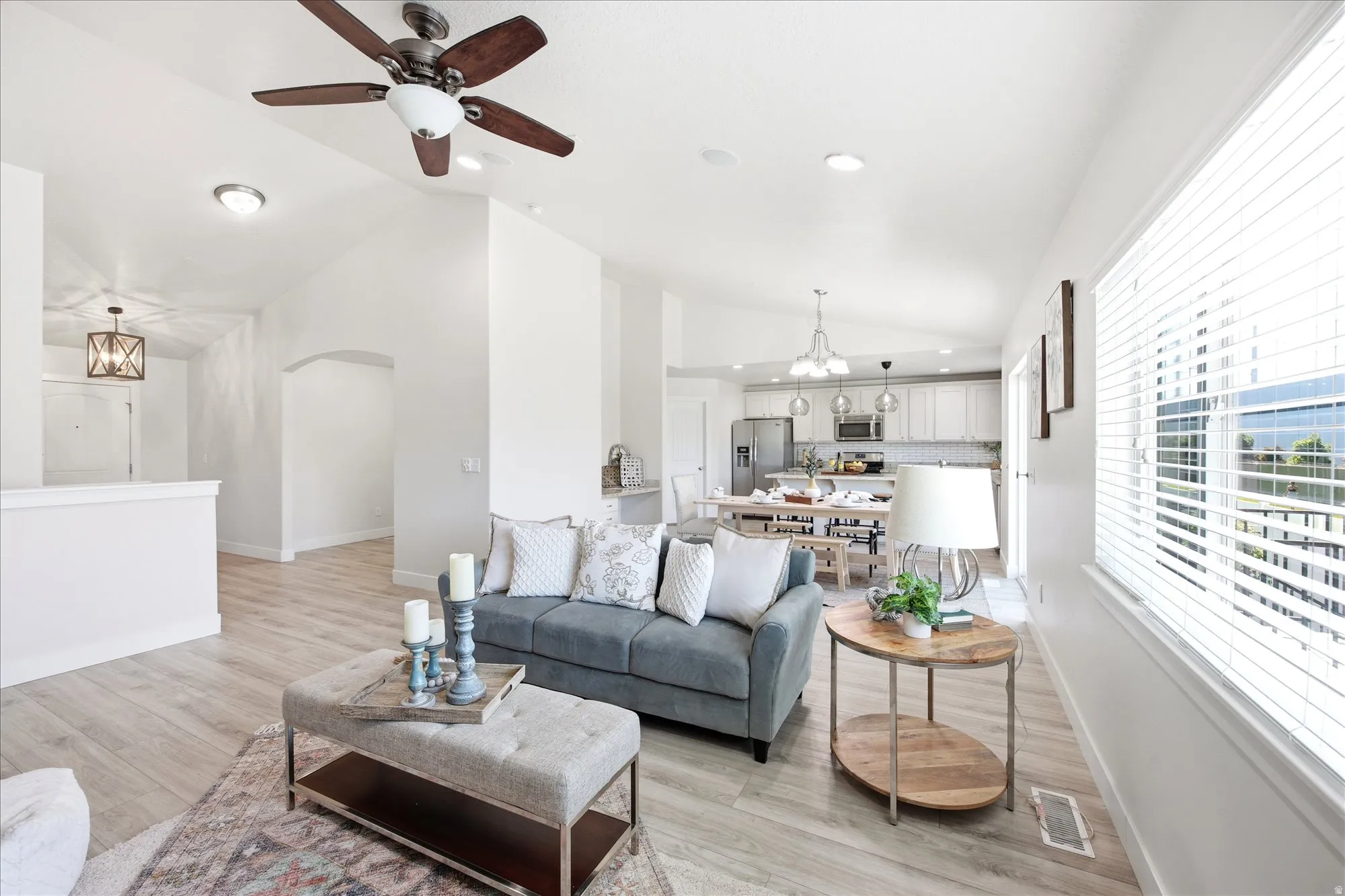 Spacious living area featuring high vaulted ceilings, light wood-finish flooring, and a contemporary ceiling fan