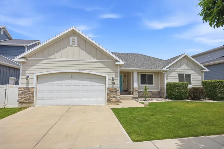 Contemporary ranch-style home featuring horizontal siding, a two-car garage, a blue front door, stone accents, and a well-maintained lawn