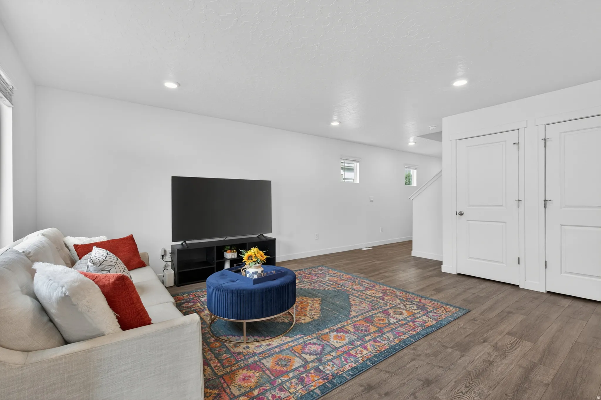 Spacious living area featuring wood-finish flooring, recessed lighting, and white walls