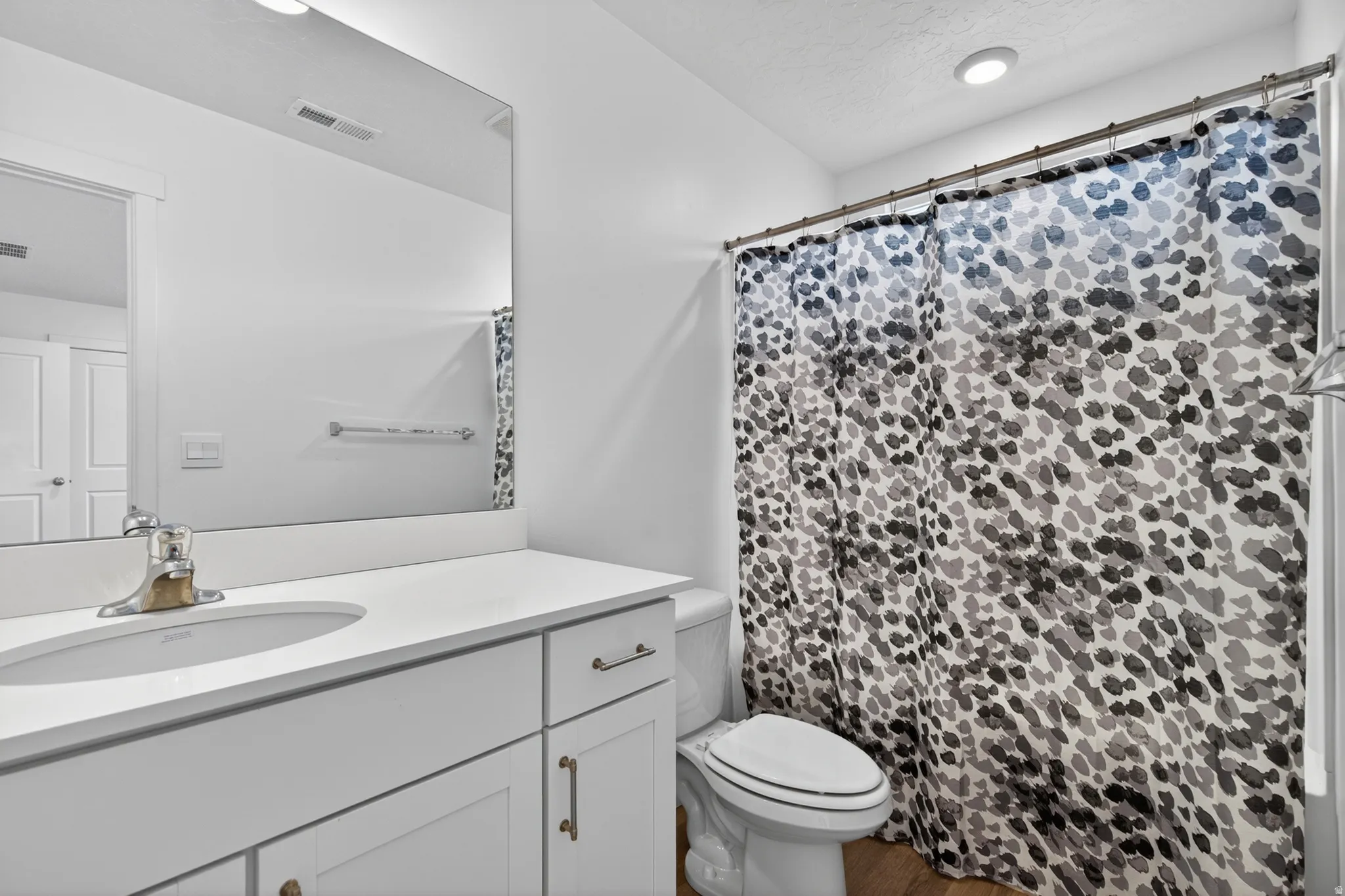 Bathroom with a white vanity featuring a single basin sink and brushed nickel faucet