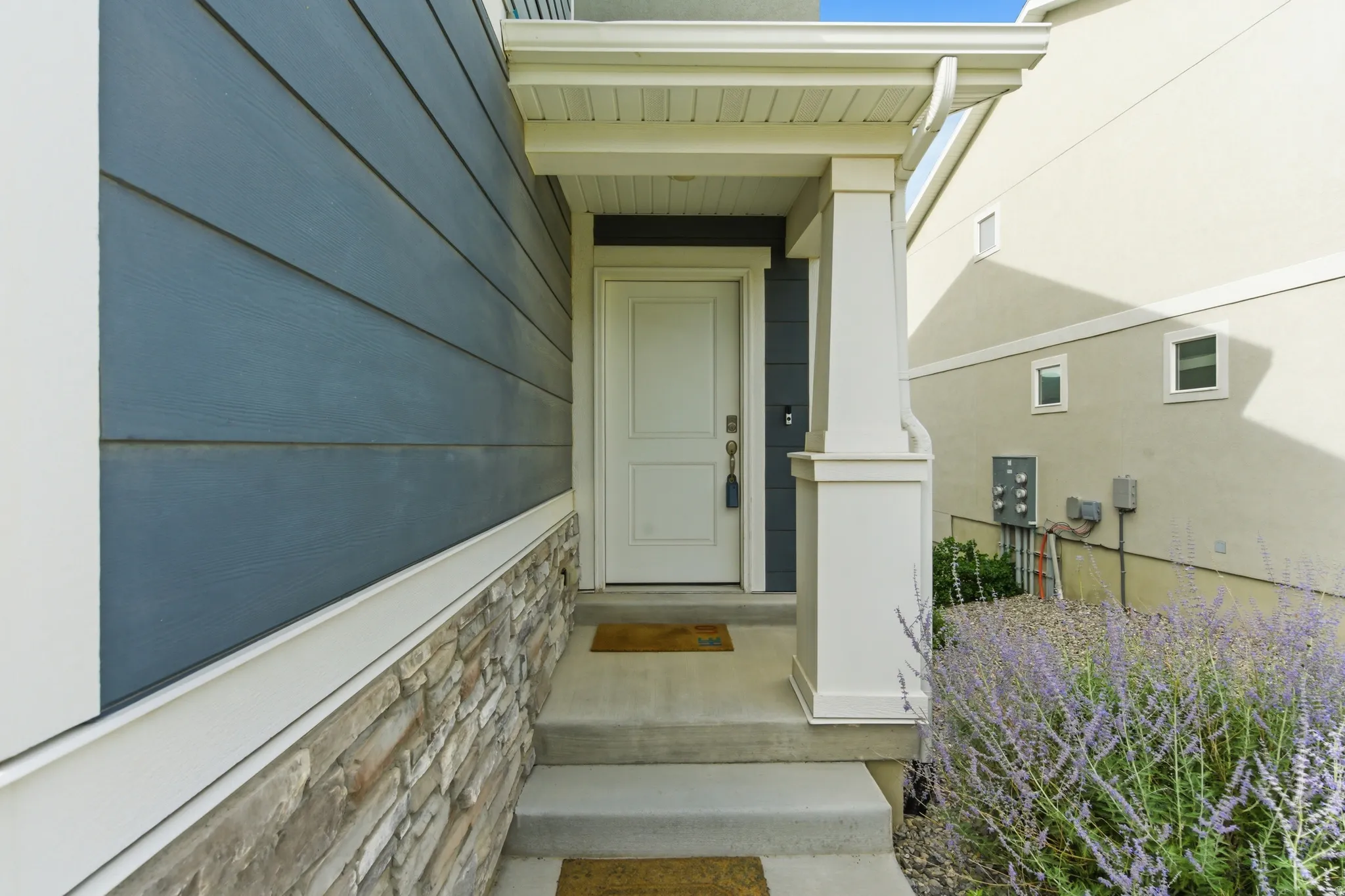 Welcoming entry featuring a white paneled door, concrete steps, and a covered porch