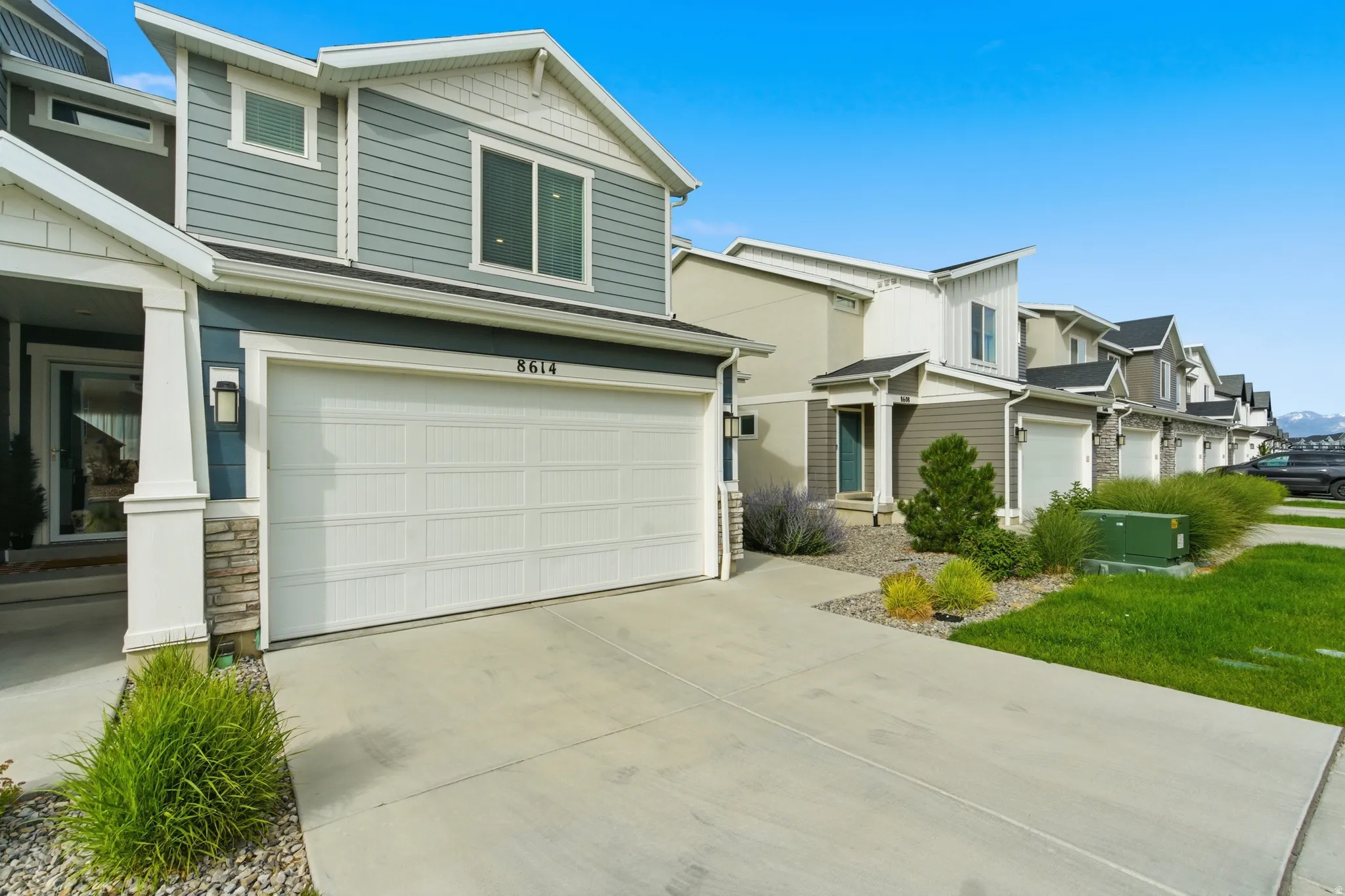 Modern residential exterior featuring blue siding, white trim, and a two-car garage