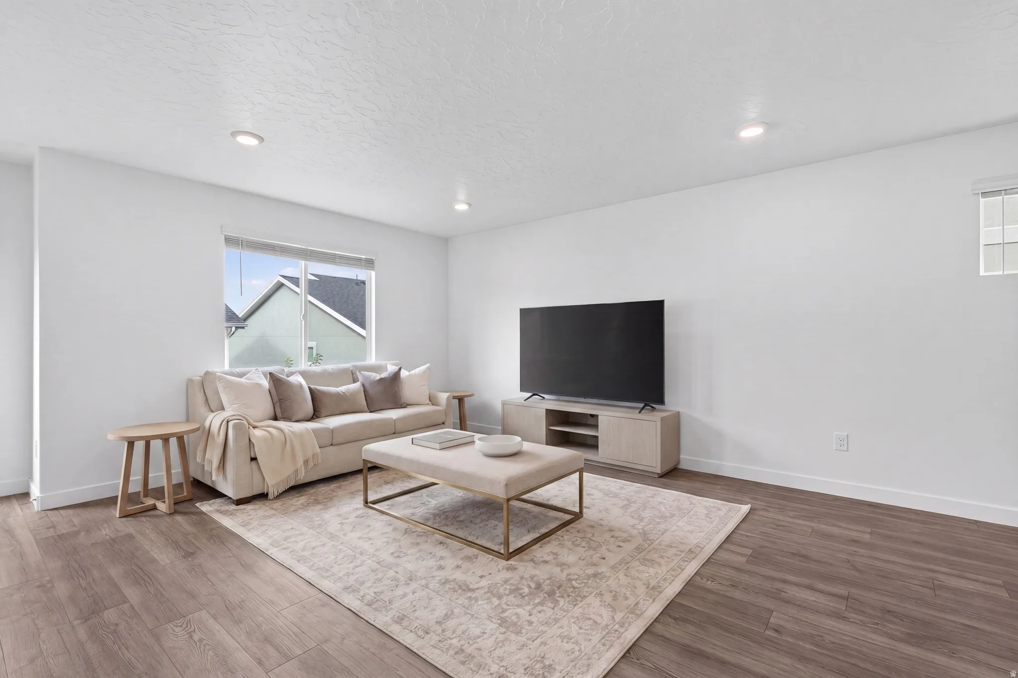 Spacious living area featuring wood-finish flooring, recessed lighting, and white baseboards