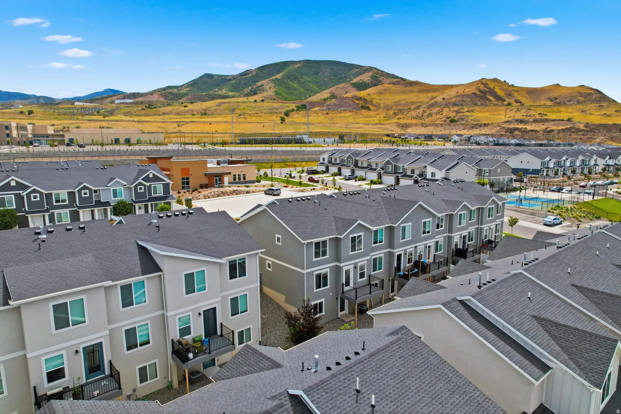 Community featuring multiple rows of multi-story townhomes, a central amenity building, and a swimming pool area