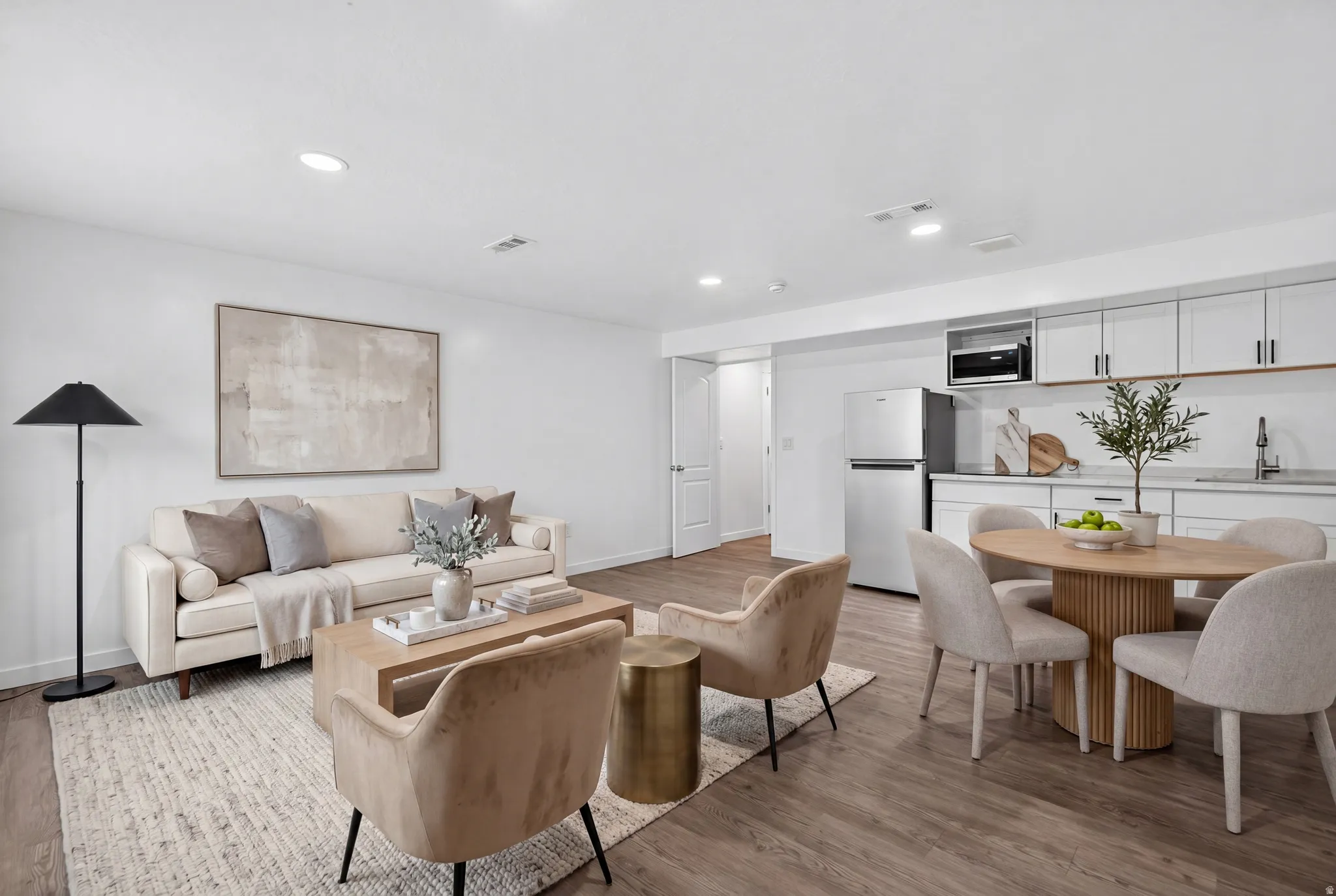 Open-concept living space featuring wood-finish flooring, recessed lighting, and a white color palette
