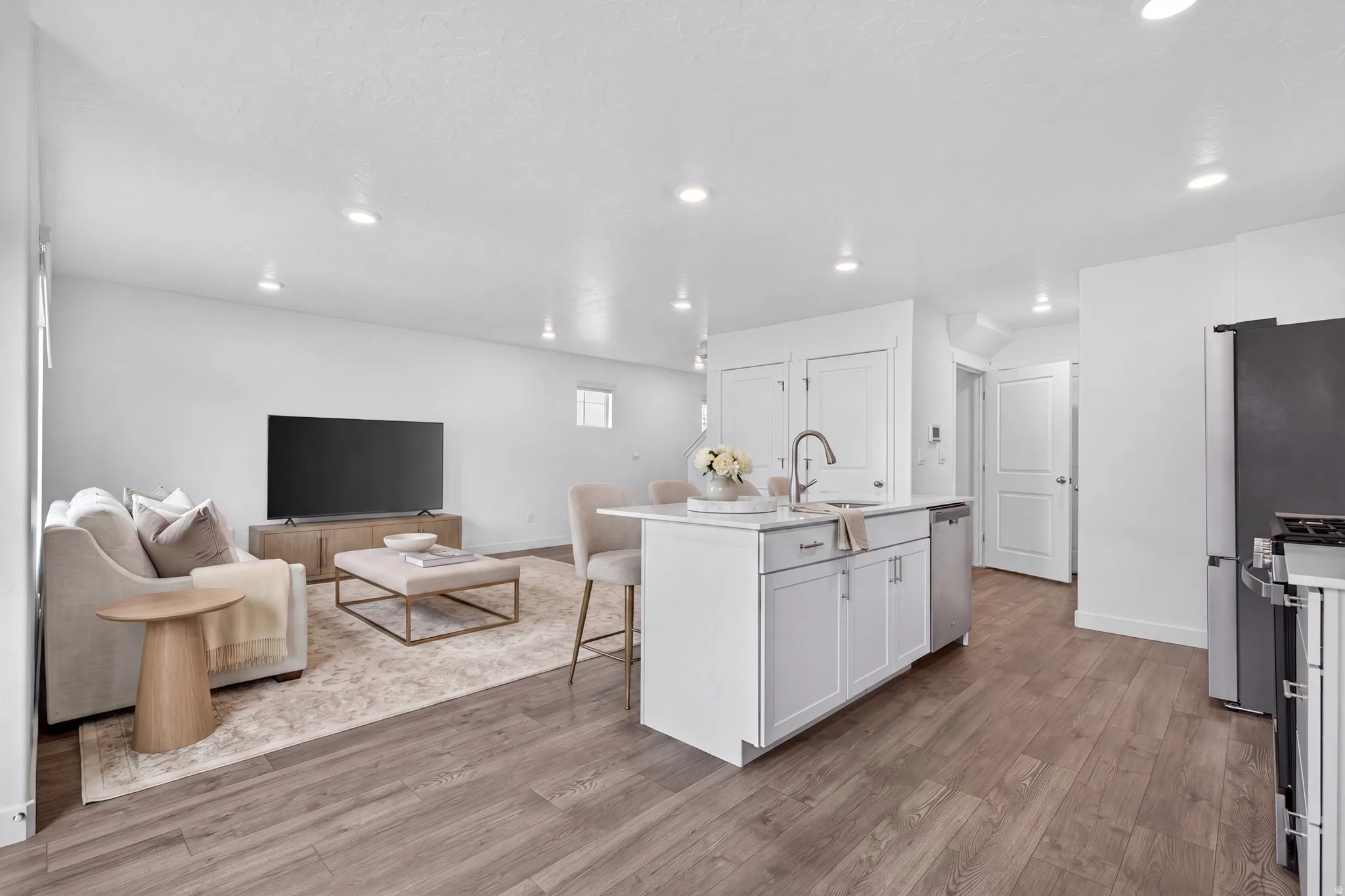 Open-concept living area with wood-finish flooring, recessed lighting, and white walls