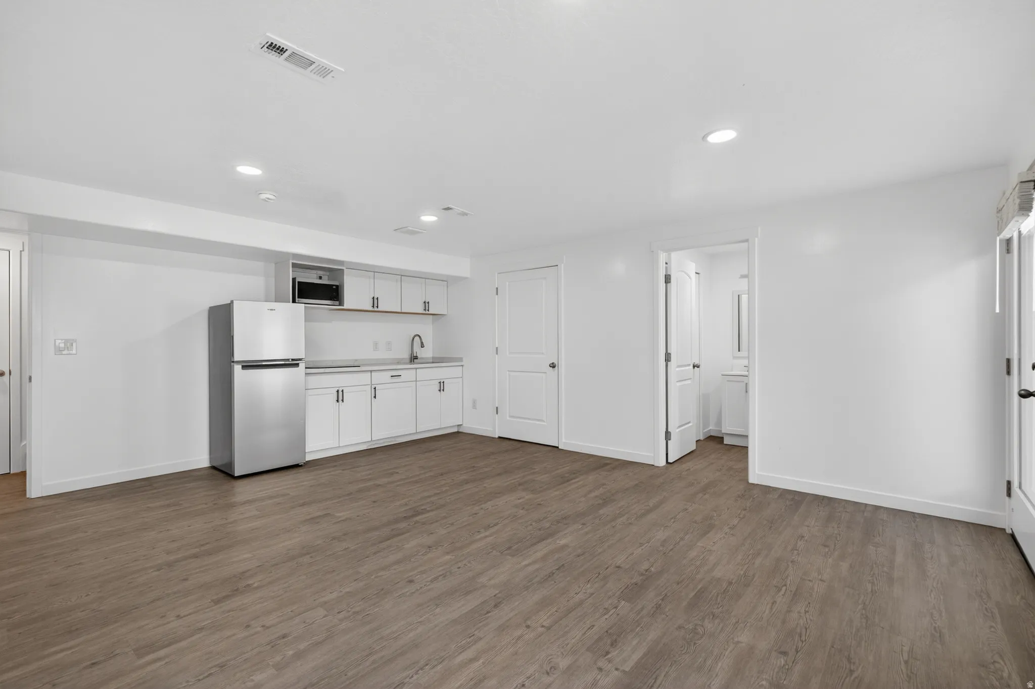Open-concept room featuring wood-finish flooring, recessed lighting, and a kitchen area