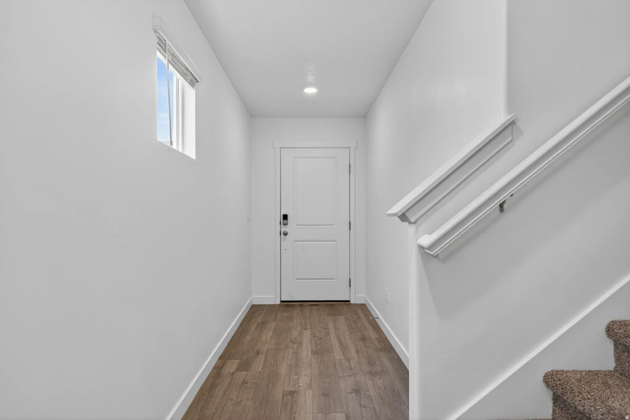 Entryway featuring wood-finish flooring, a white paneled door with a smart lock, and a window for natural light