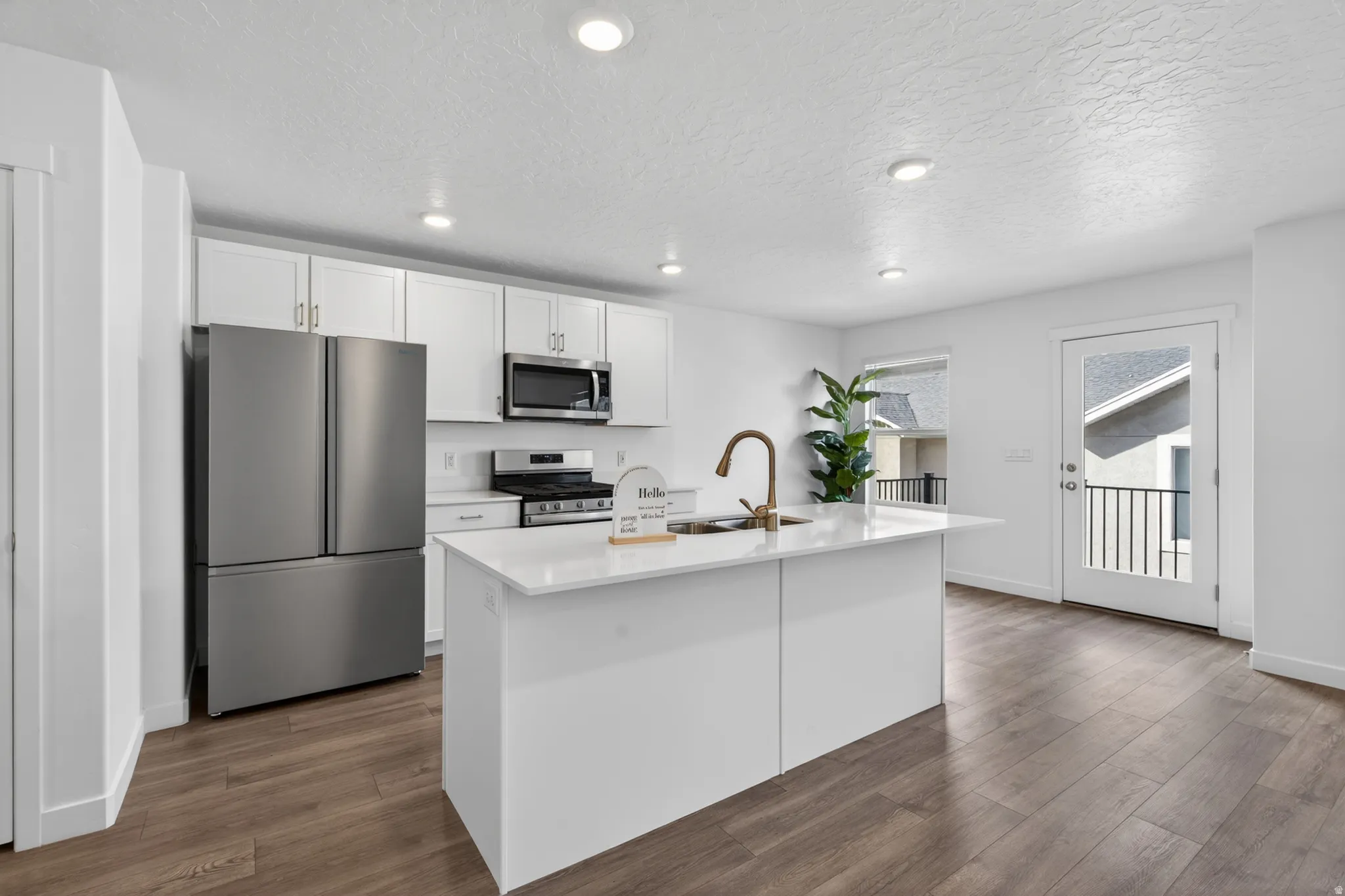 Open-concept kitchen featuring white cabinetry, stainless steel appliances, and wood-finish flooring