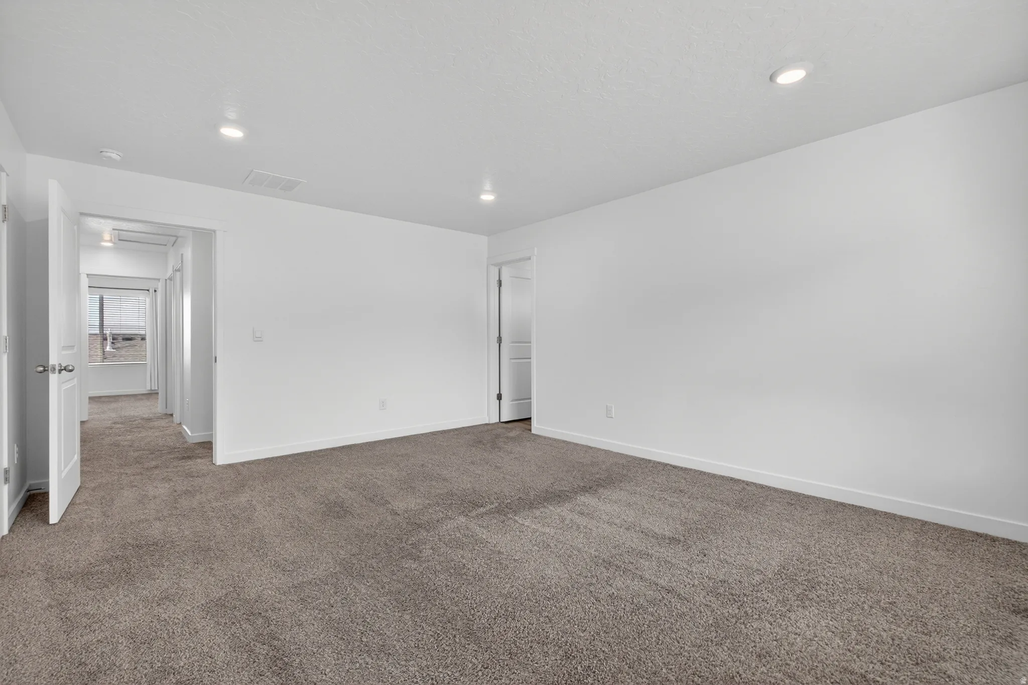Spacious carpeted room featuring recessed lighting, white walls, white trim, and white doors