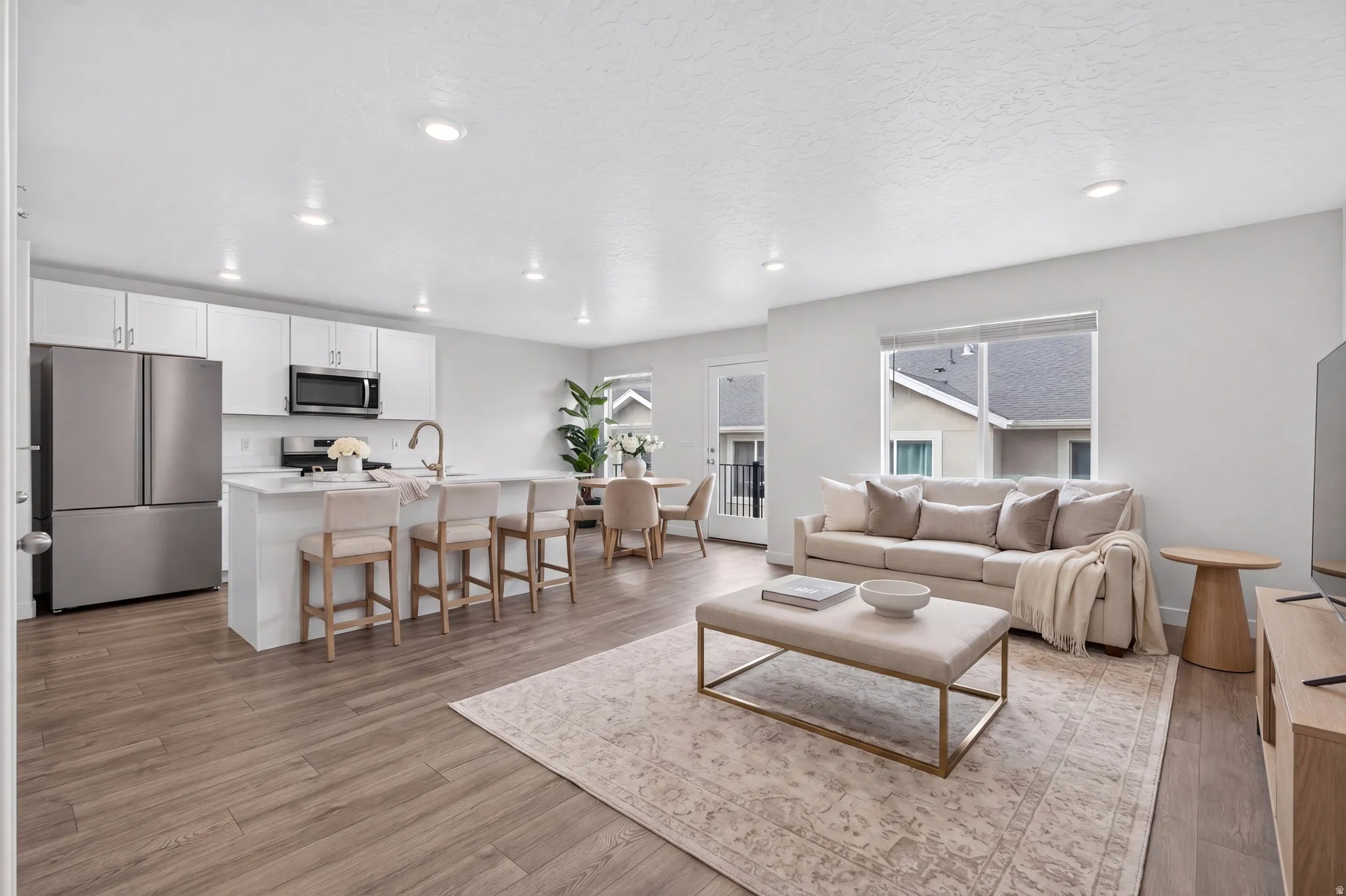 Open-concept living area featuring wood-finish flooring, recessed lighting, and a neutral color palette