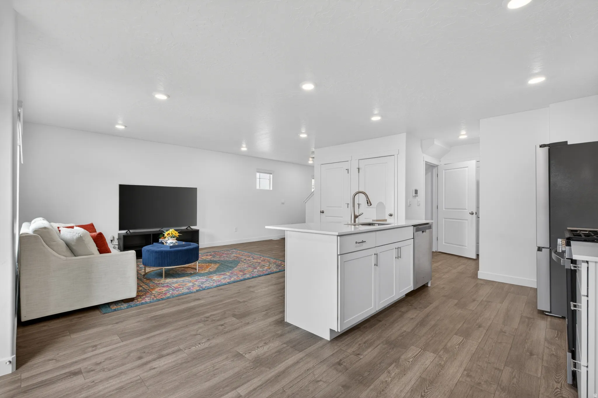 Open-concept living space featuring wood-finish flooring, recessed lighting, and white walls
