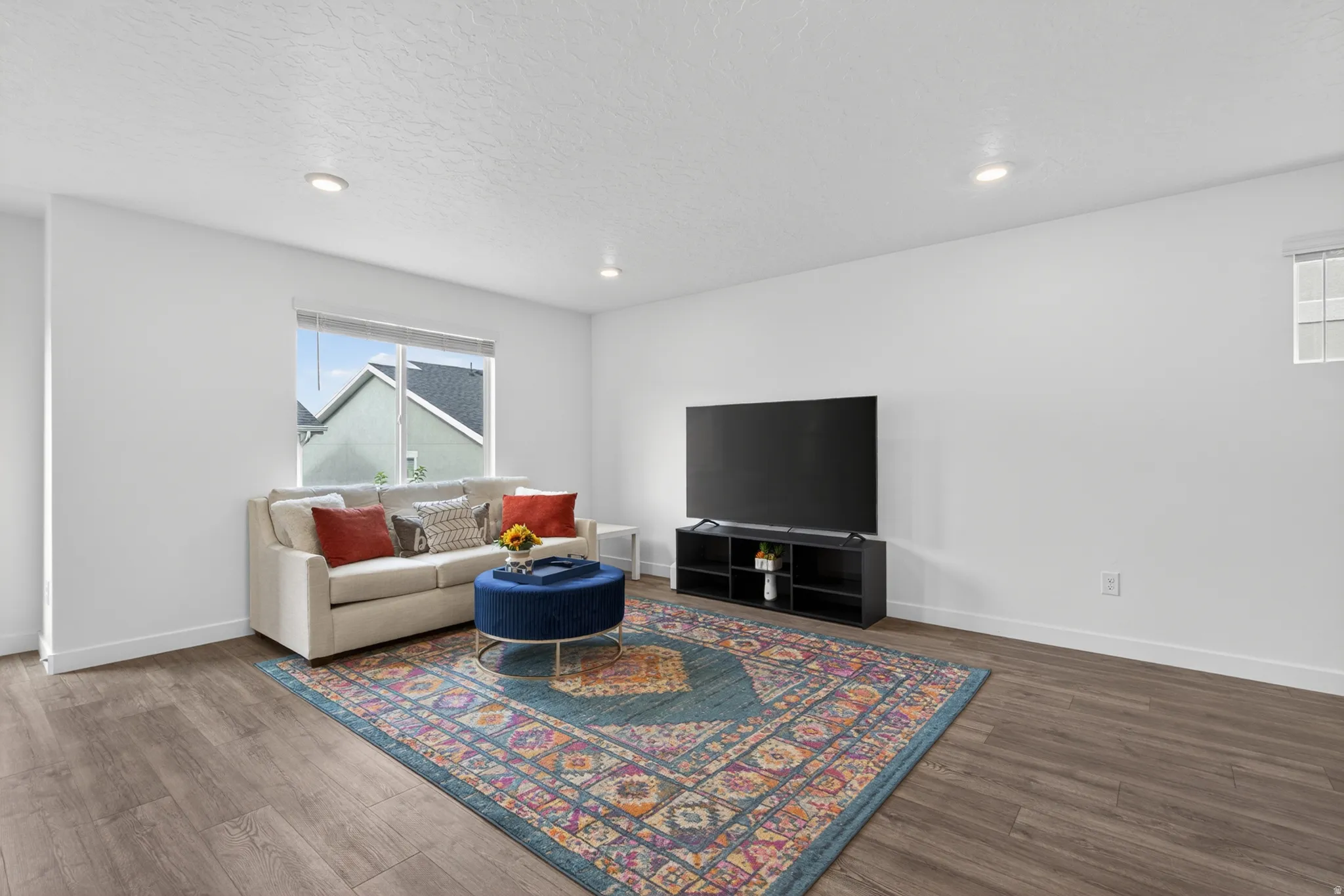 Spacious living area featuring wood-finish flooring and recessed lighting