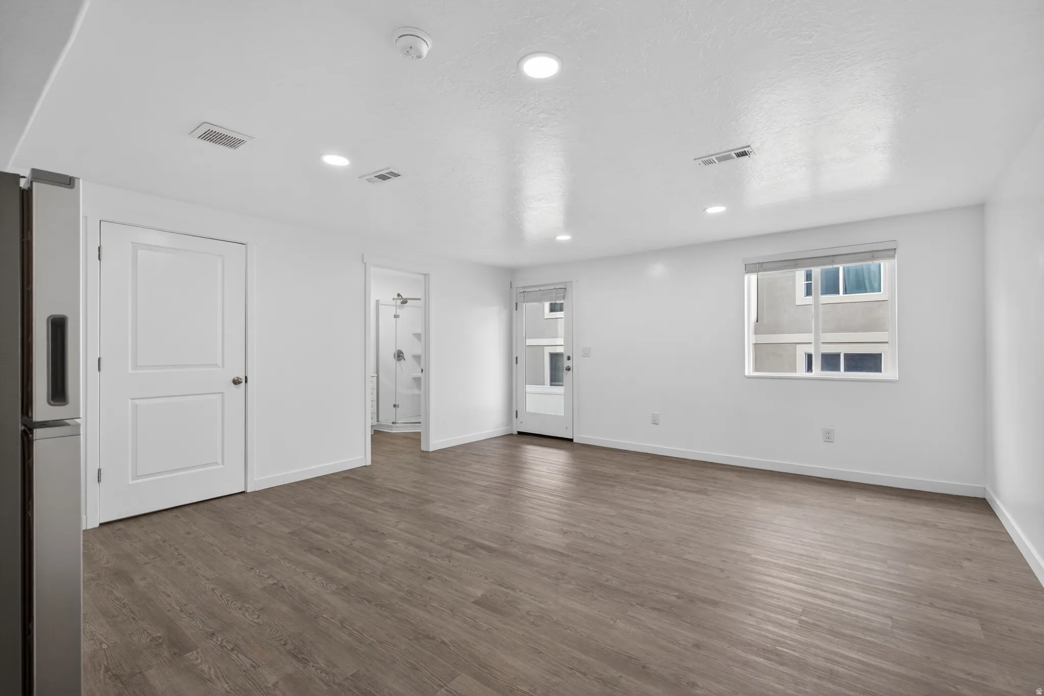 Spacious room featuring wood-finish flooring, recessed lighting, and a white interior paint scheme
