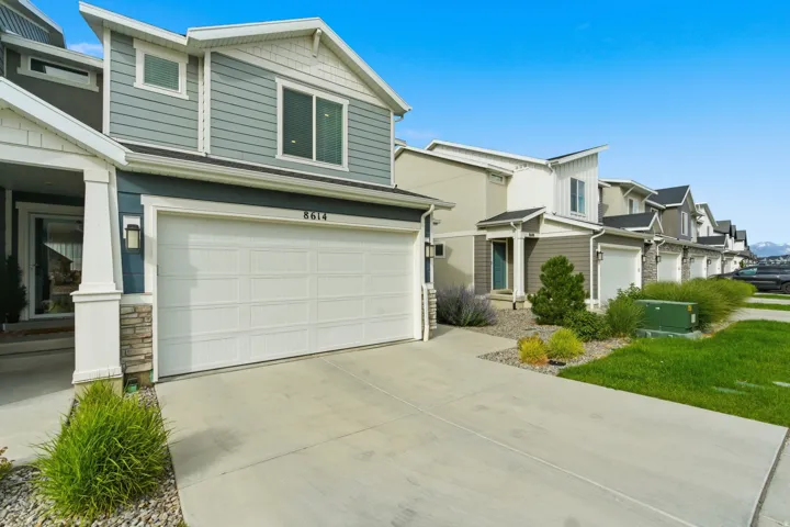 Modern residential exterior featuring blue siding, white trim, and a two-car garage