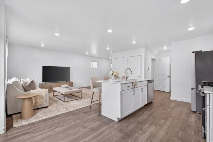 Open-concept living area with wood-finish flooring, recessed lighting, and white walls