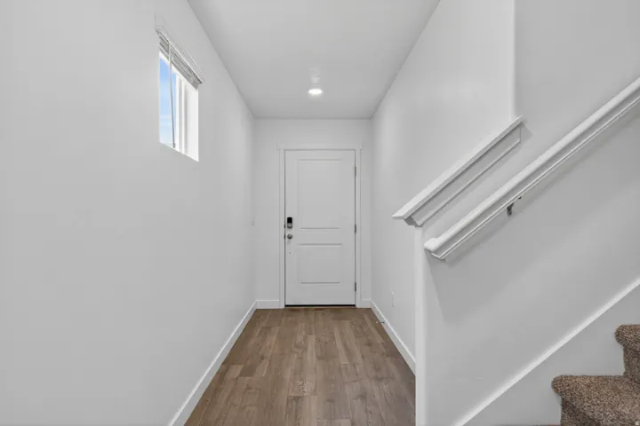 Entryway featuring wood-finish flooring, a white paneled door with a smart lock, and a window for natural light