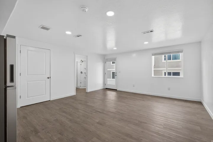 Spacious room featuring wood-finish flooring, recessed lighting, and a white interior paint scheme