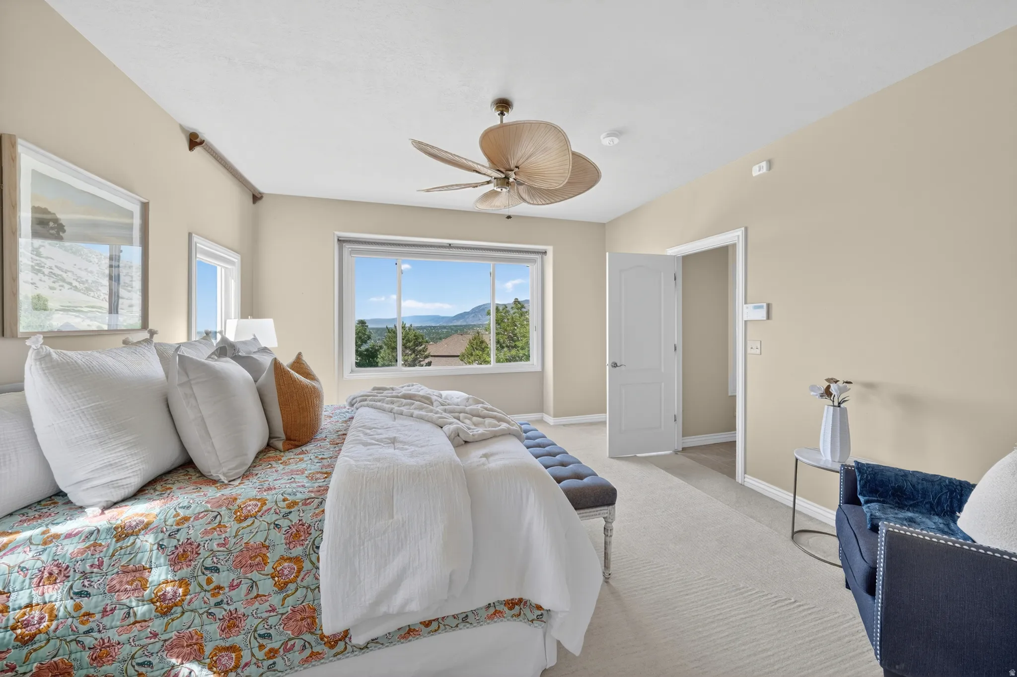 Primary bedroom featuring broad windows with mountain scenery, a unique ceiling fan, and light-toned wall paint
