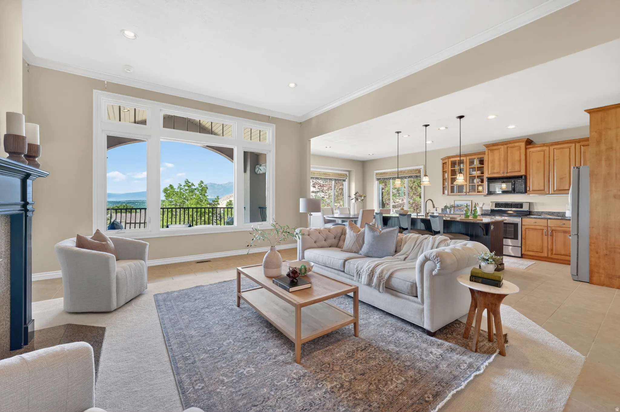 Open-concept living area featuring a large picture window, a fireplace with a dark mantle, recessed lighting, and crown molding