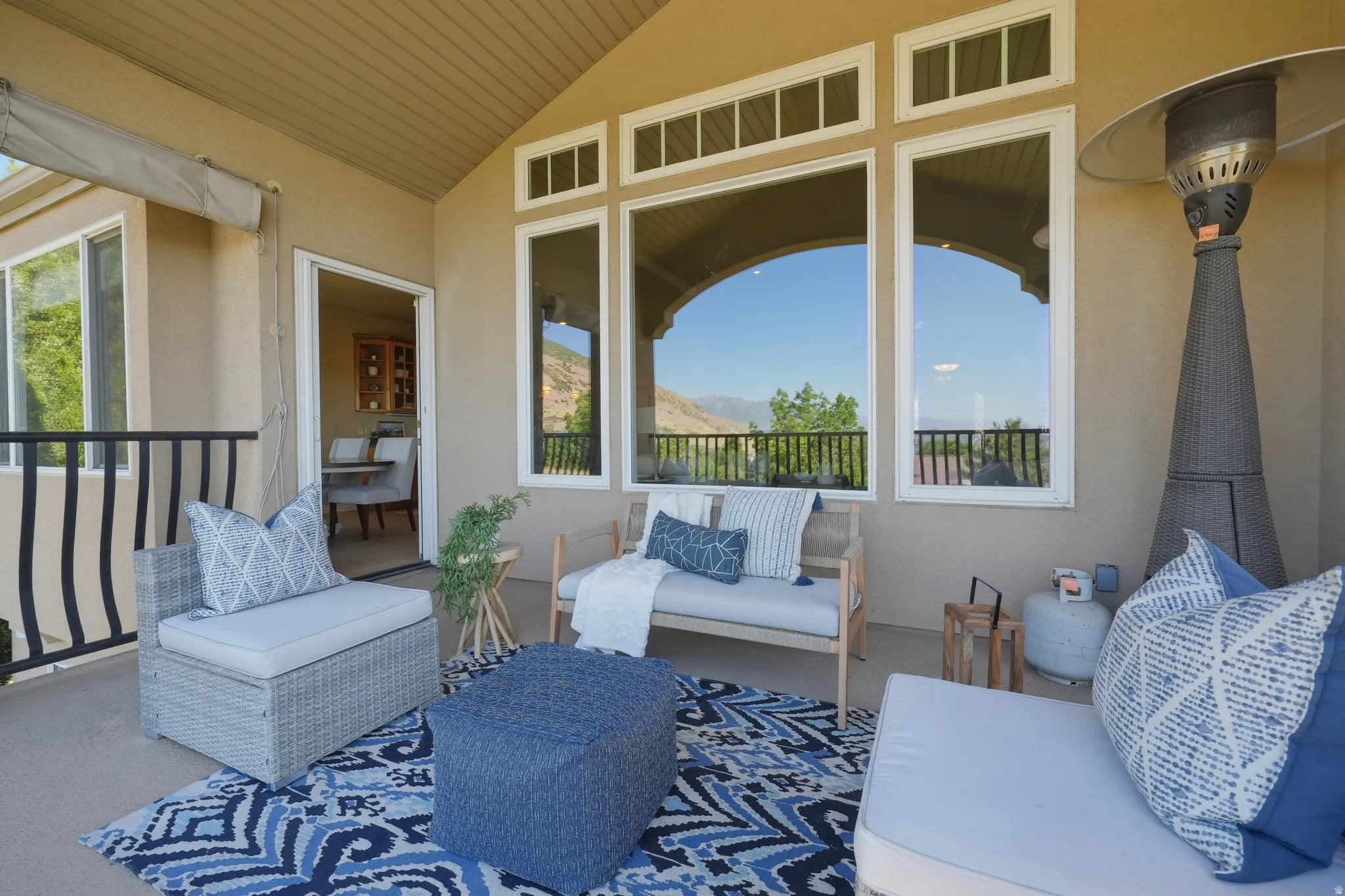 Covered patio space off of kitchen and living room featuring a vaulted ceiling and stucco exterior with mountain and valley views