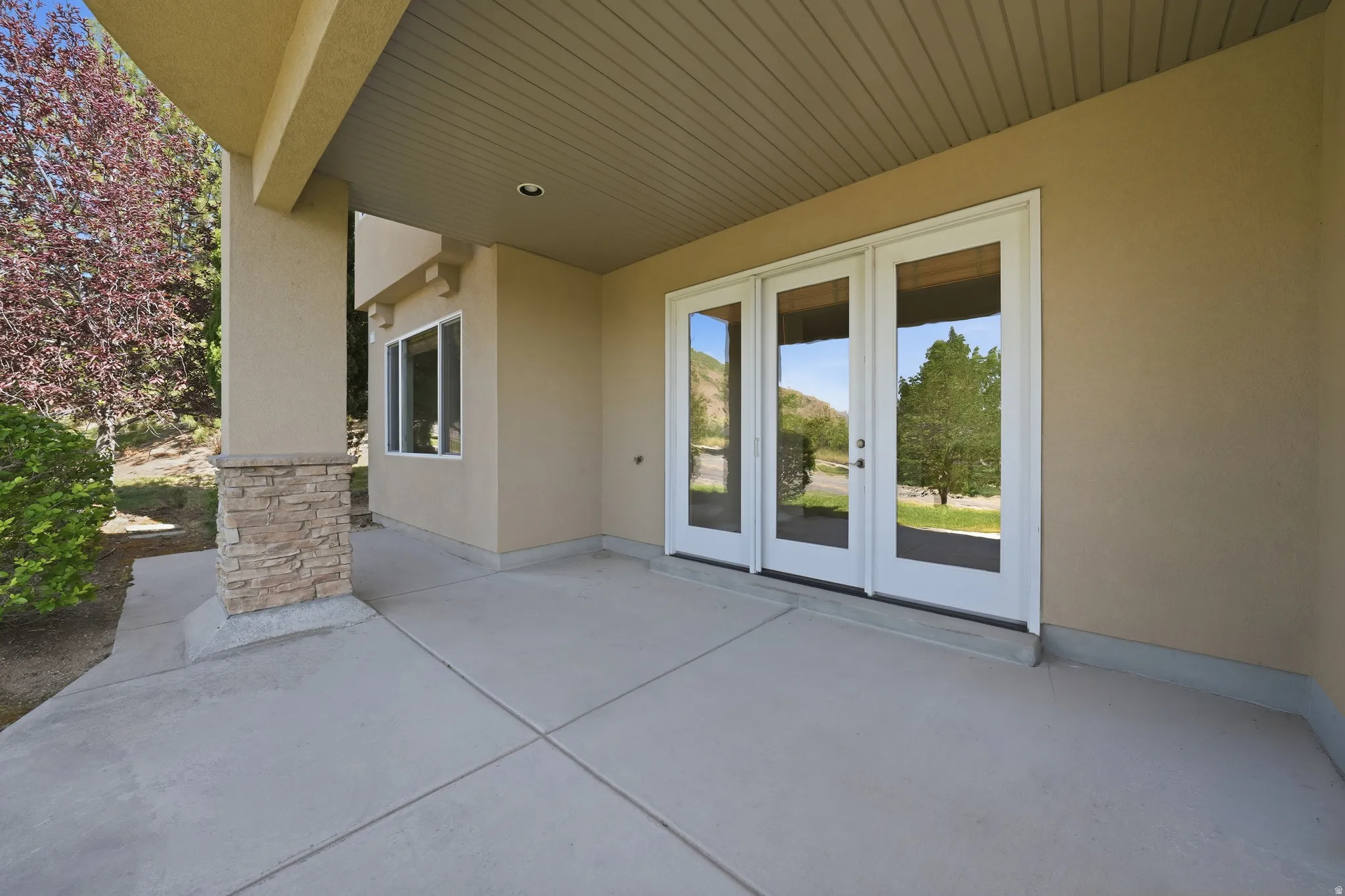 Concrete patio featuring multiple French doors and a stucco exterior