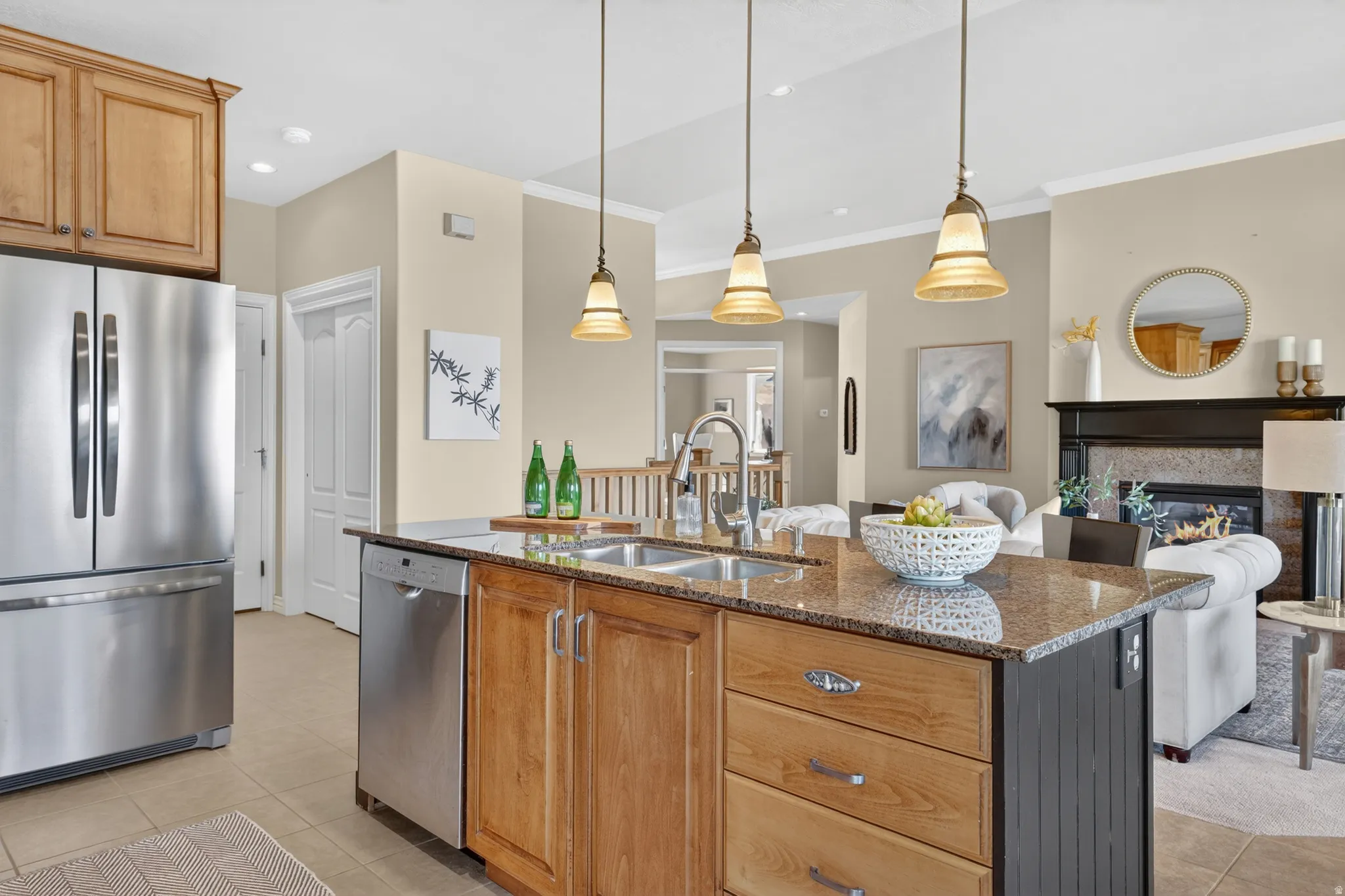 Kitchen island featuring a double-basin stainless steel sink, granite countertop, and pendant lighting