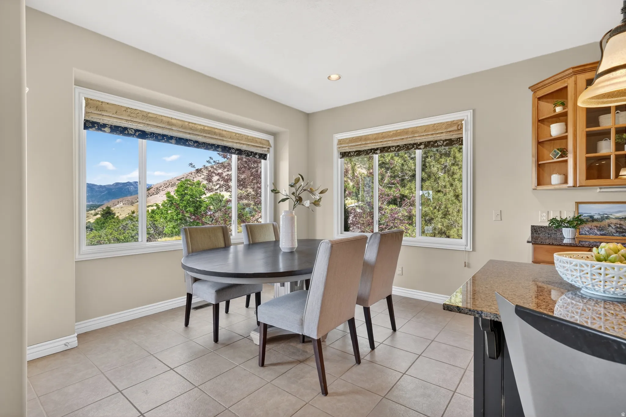 Tile flooring with a neutral finish, featuring multiple large windows, natural wood built-in cabinetry, and a granite countertop