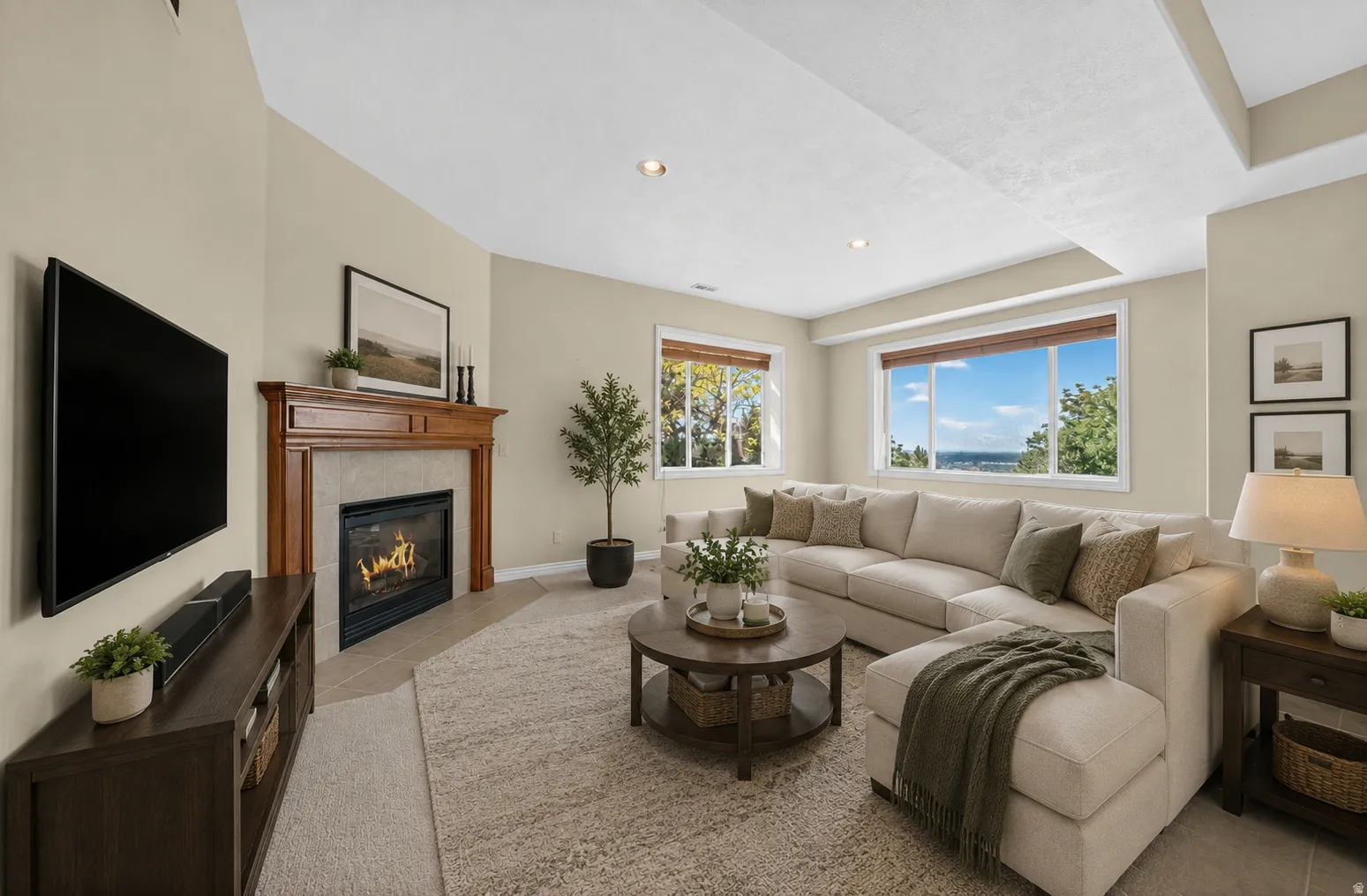 Spacious living area featuring a traditional fireplace with wood mantel and tile surround, recessed lighting, and multiple large windows