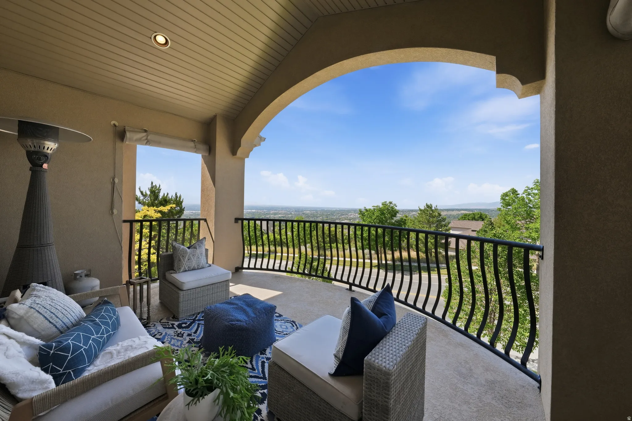 Curved balcony featuring black iron railings, a textured stucco exterior and a planked ceiling with recessed lighting with sweeping mountain and valley views