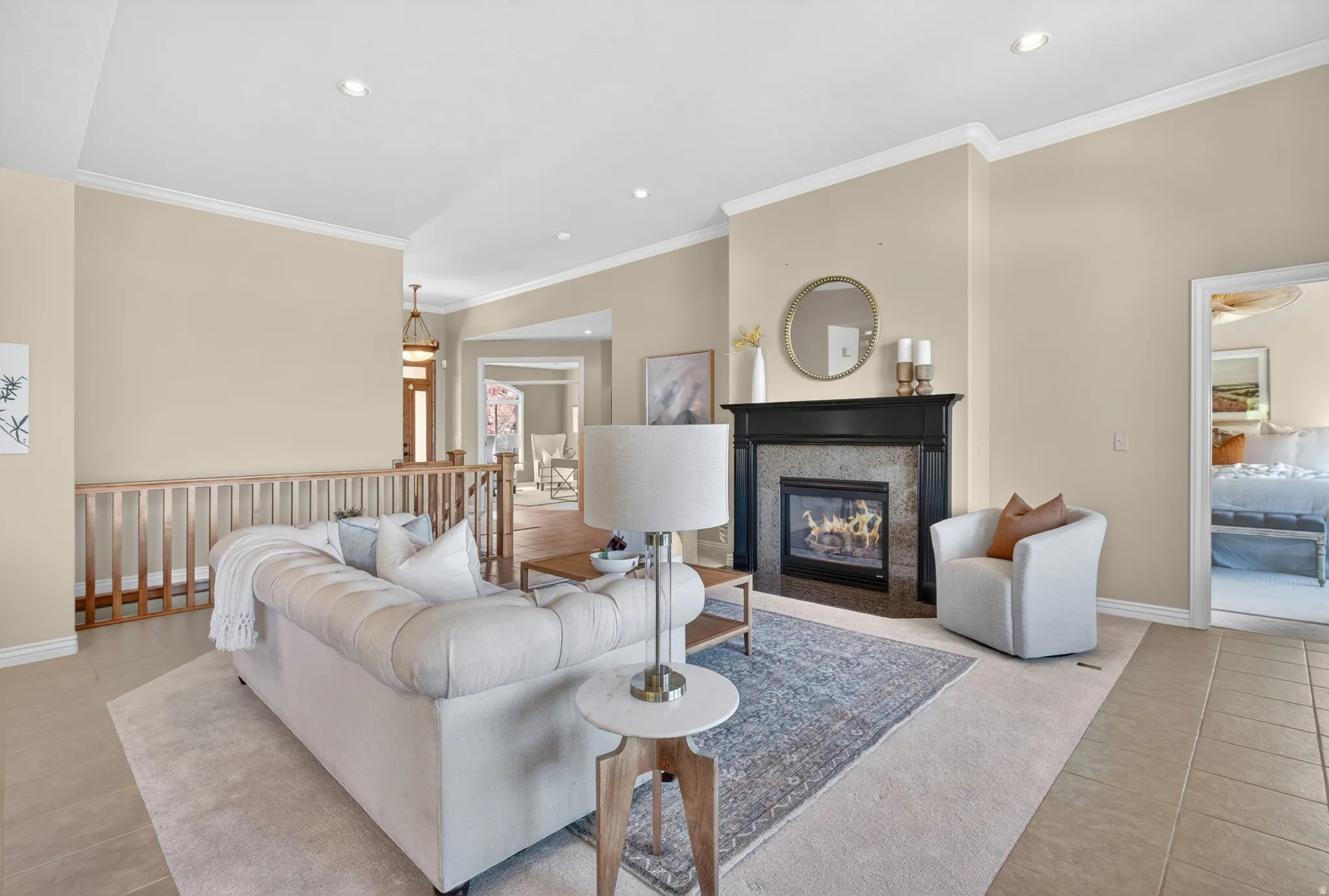 Living area featuring a black mantel fireplace with stone surround, recessed lighting, crown molding.