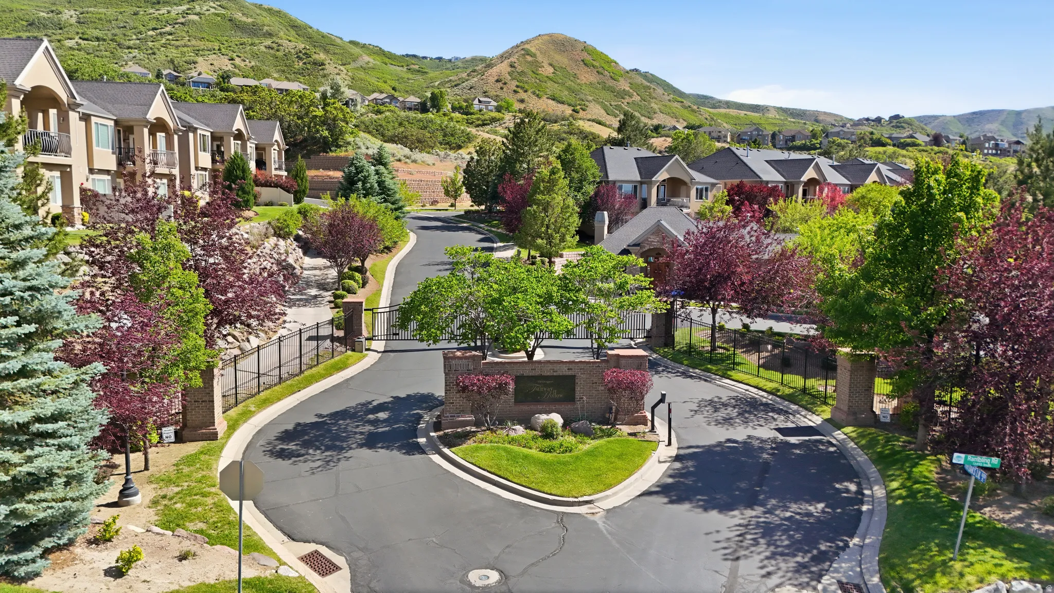Entrance featuring stone pillars, decorative iron gates, and mature landscaping